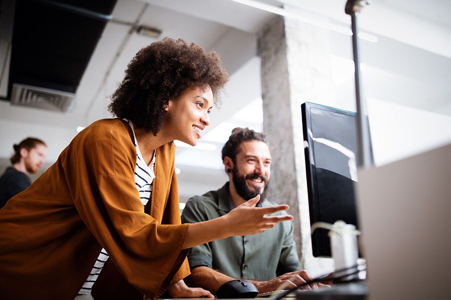 Client Center - Two Smiling Employees Working on Computer in the Office